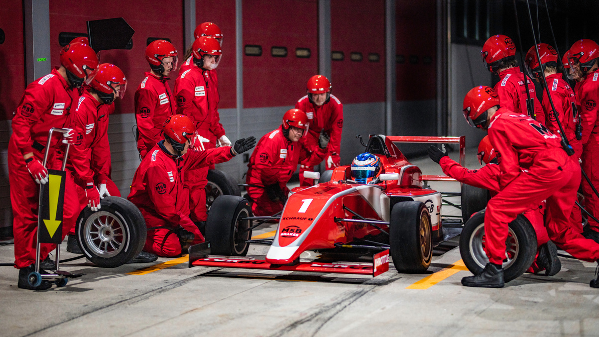 Pit crew preparing to change tires on formula car