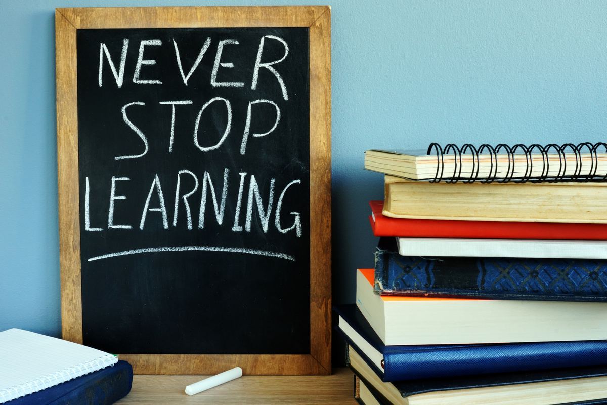 Blackboard with sign Never stop learning and books.